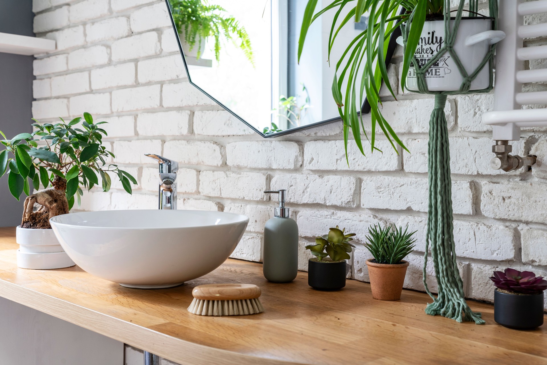 Modern interior of bathroom in industrial style with plant and brick wall in loft apartment.